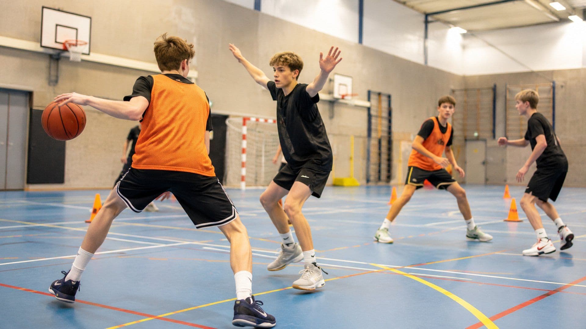 Jonge basketballers in een oefening met tegenstand in een sporthal