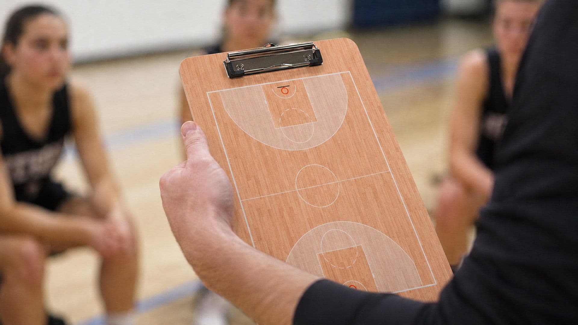Hand van een coach die een coachbord met opgedrukt speelveld vasthoudt voor het team