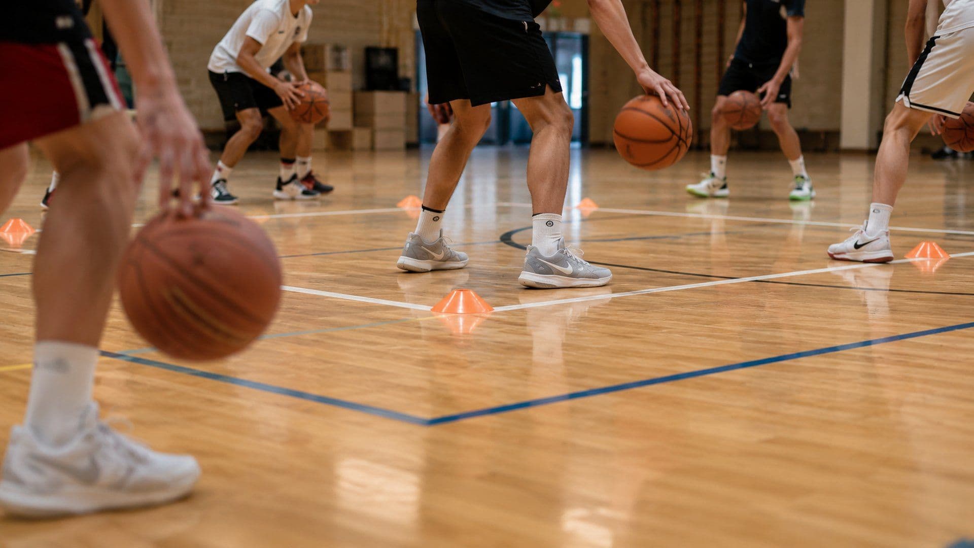 Spelers dribbelen tussen pionnen tijdens de warming-up van een basketbaltraining